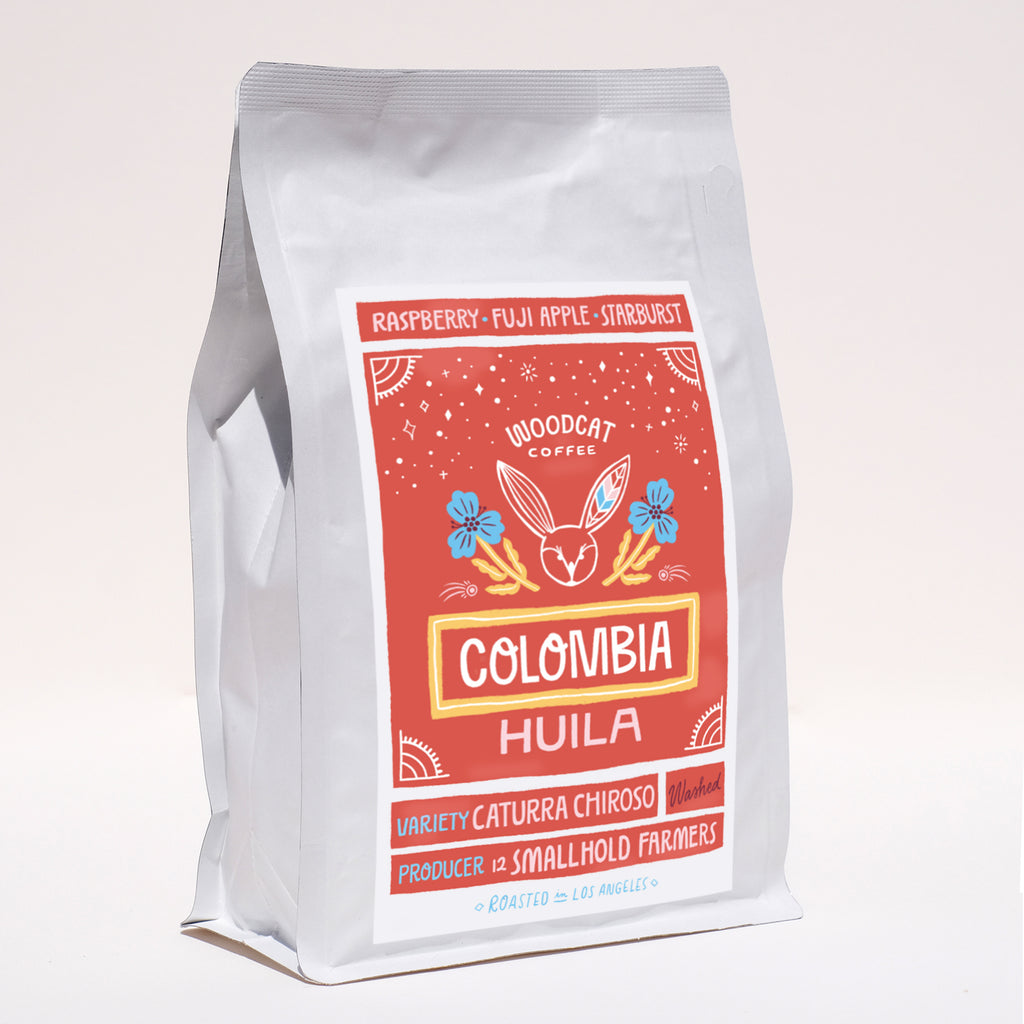 A sideview of a white coffee bag with a red label that reads "colombia huila"