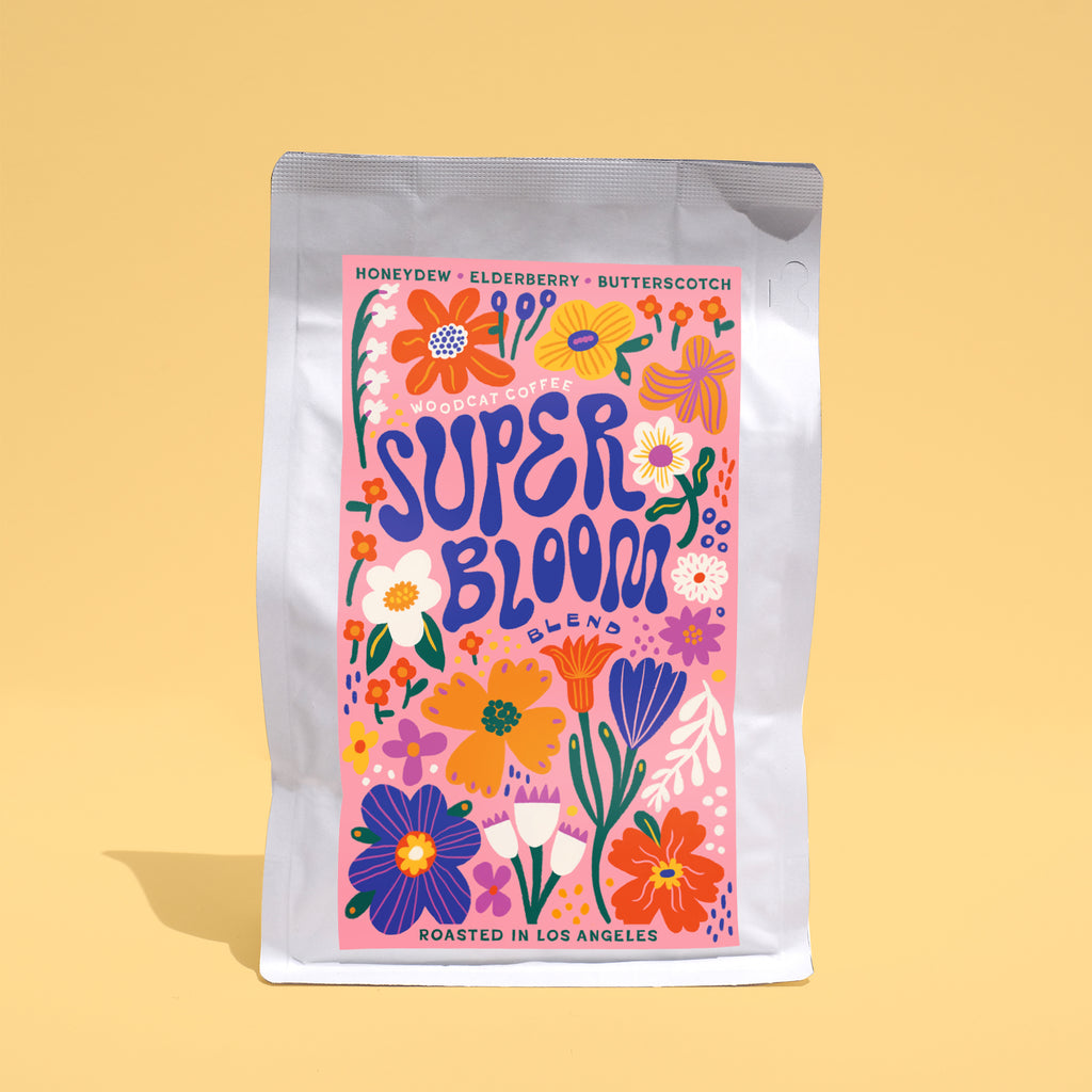 A small white paper bag on a yelllow background with a colorful floral label