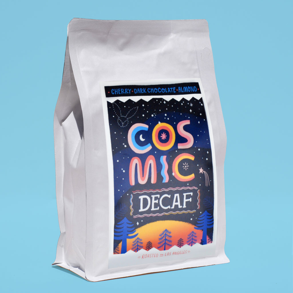 A side view of a white bag of coffee with a blue label that reads "cosmic decaf"