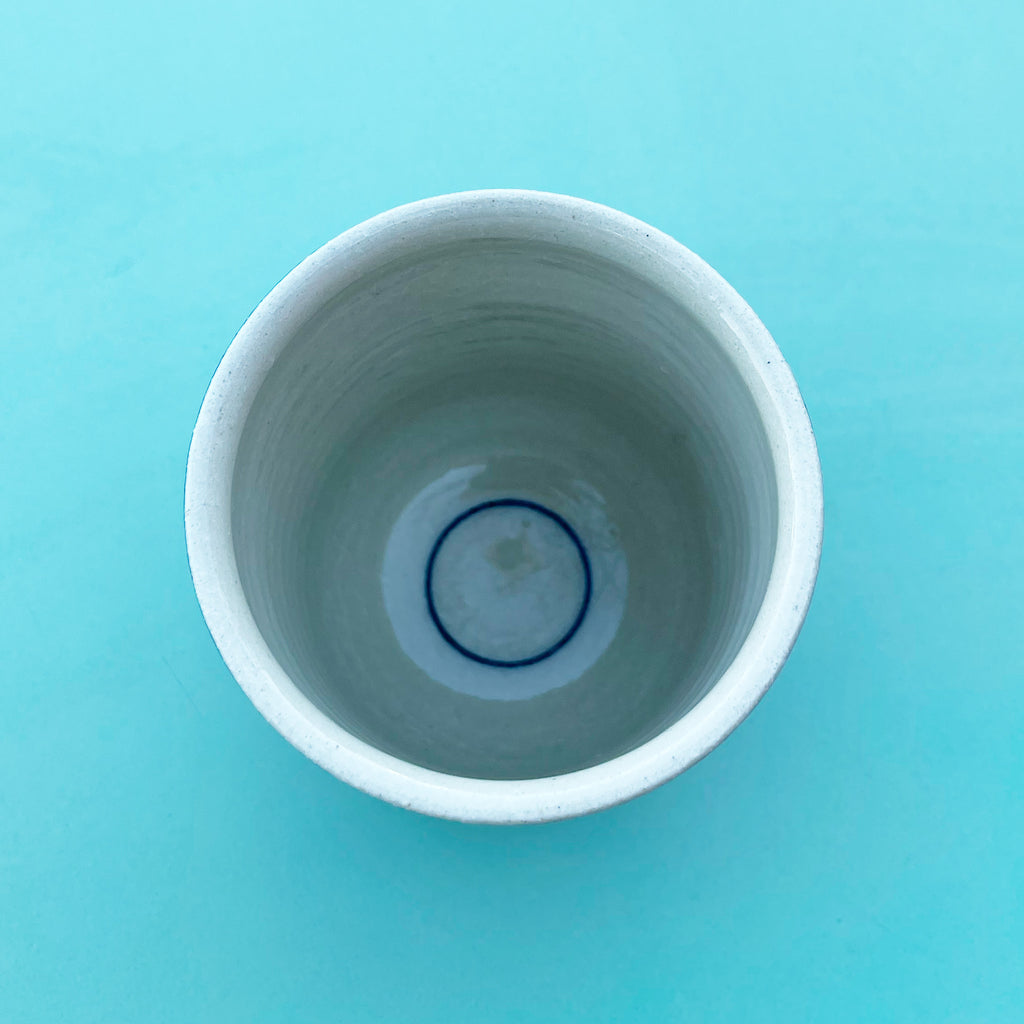 A blue ring painted inside the bottom of a white cup