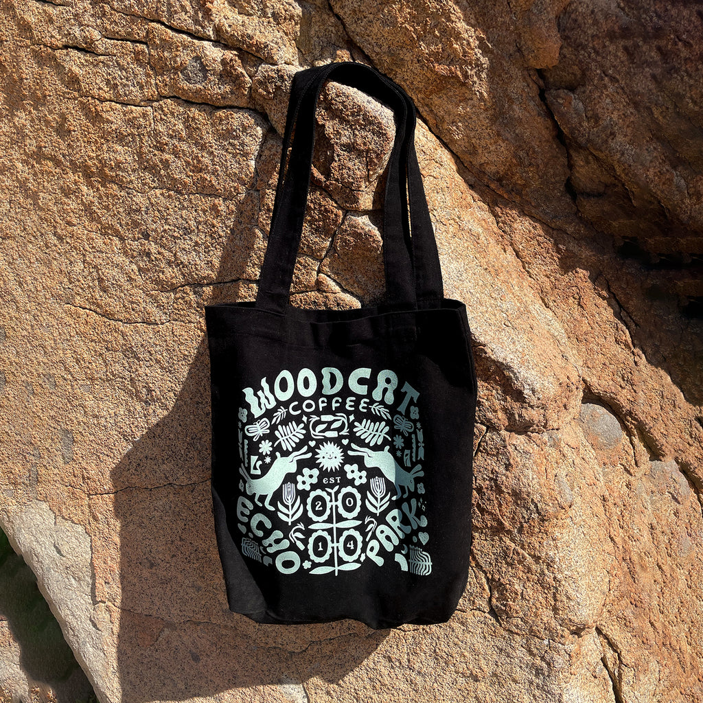 a black tote bag with a light blue design hung from a rock cliff